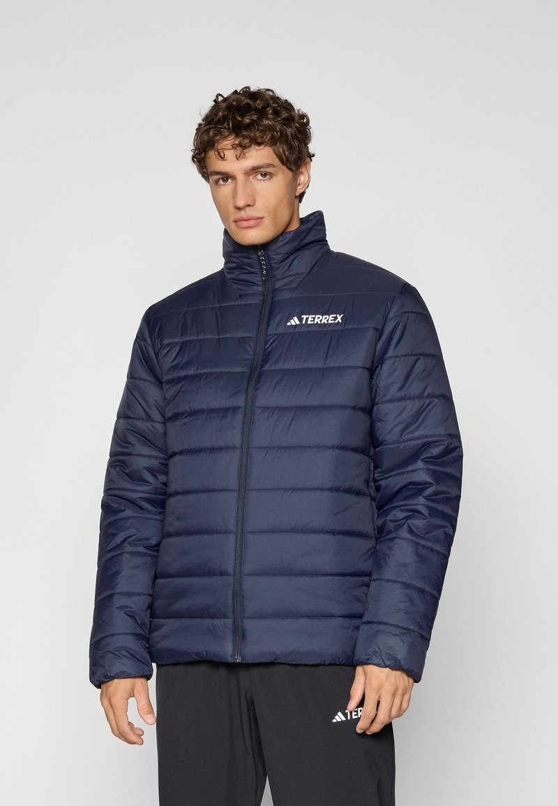 Chaqueta tipo plumas en color navy con un alto cuello, patrón de acolchado horizontal, cremallera frontal y logo de Terrex en el lado izquierdo del pecho.