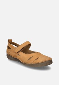 Chaussure Mary Jane en cuir marron clair avec bride réglable, détails découpés et semelle marron foncé, présentée en angle sur fond gris clair.
