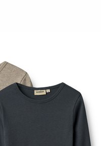 Deux chemises à manches longues : une gris foncé avec une texture côtelée et une beige avec une finition lisse, toutes deux dotées de cols ronds et d'étiquettes.