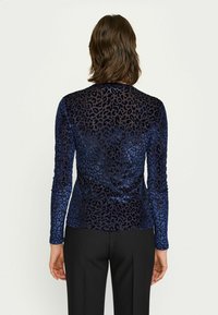 Tumesinine pikkade varrukatega shirt, millel on leopardimuster. Valmistatud siledast sametist, sobiv disain ümmarguse kaelusega ja ilma õmblusteta õlgadega.