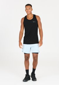 Svart linne, ljusblå shorts med sidoklipp, svarta strumpor och svarta sneakers. Linnet har subtila vita linjeaccenter.