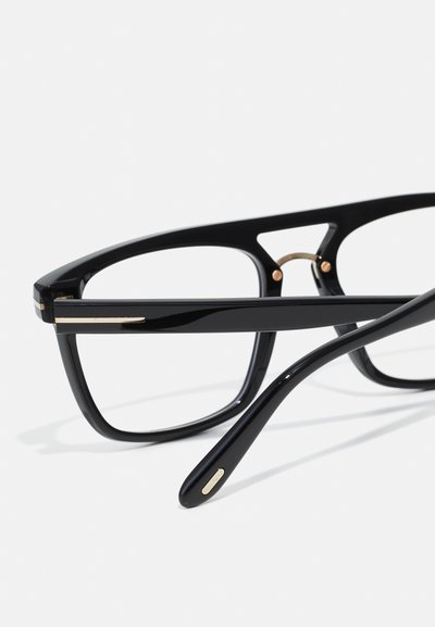 Óculos de acetato pretos com uma armação retangular, apresentando detalhes em dourado nas hastes e na ponte. Textura suave, design moderno.