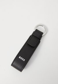 Black leather keychain with a textured finish, featuring a silver metal ring and a loop for attachment. "BOSS" logo in white on strap.
