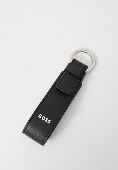 Porte-clés en cuir noir avec une finition texturée, doté d'un anneau en métal argenté et d'une boucle pour l'attache. Logo "BOSS" en blanc sur la sangle.