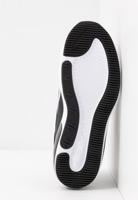 Black and white athletic shoe sole with textured rubber for grip, featuring a distinct pattern, branding, and a smooth central area.