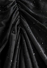 Tissu noir avec une surface texturée présentant des sections froncées et des strass brillants éparpillés partout. Matériau doux, lisse et léger.