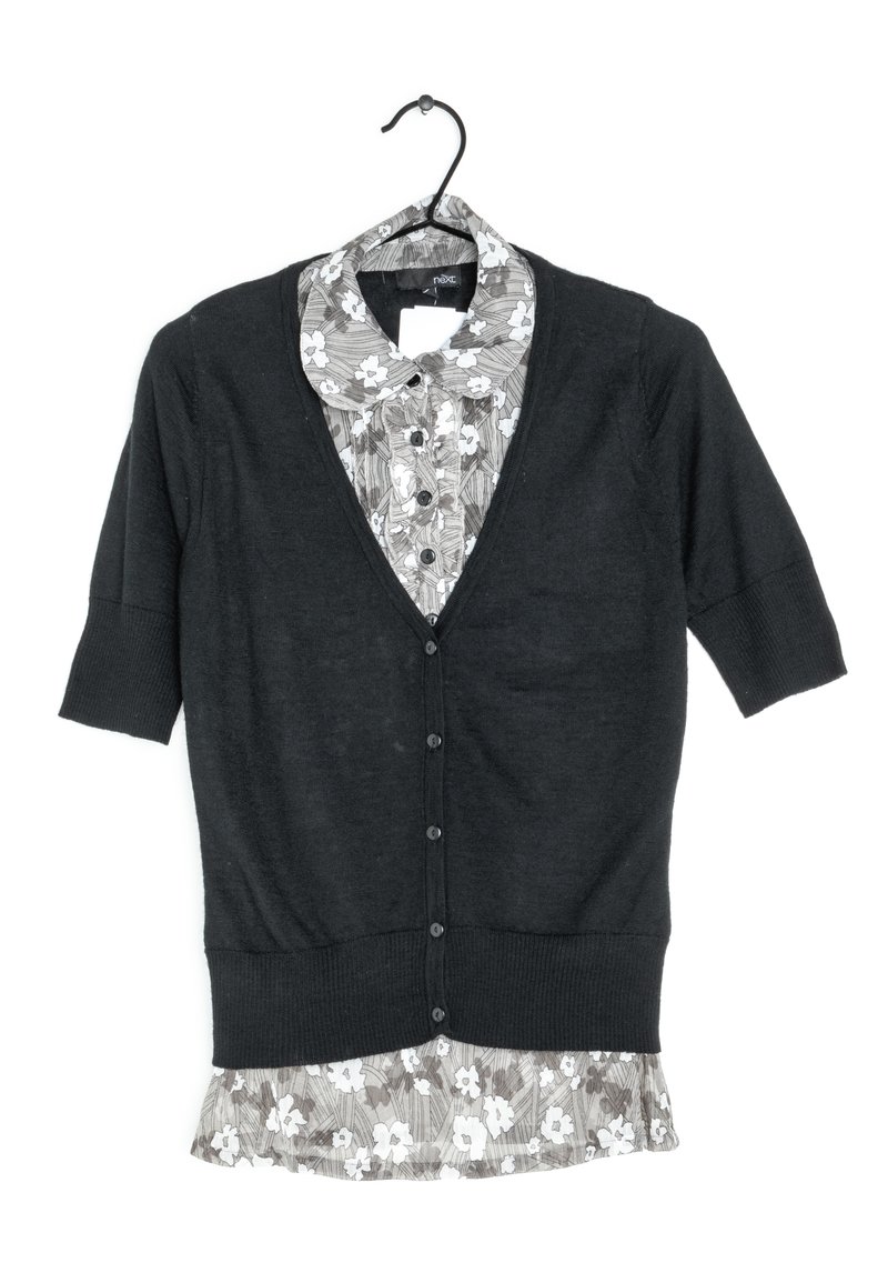 Black cardigan with short sleeves, featuring a V-neck and button closure, layered over a gray floral-patterned shirt with a round collar.