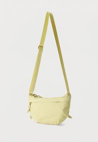 Φως πράσινη τσάντα χιαστί με ρυθμιζόμενο ιμάντα, κλείσιμο με φερμουάρ και λεπτομέρειες με δεμένα κορδόνια στα πλαϊνά, σε λευκό φόντο.