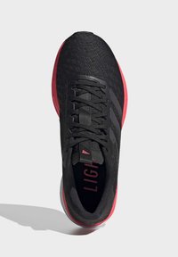 Scarpa sportiva nera con una tomaia texturizzata, caratterizzata da tre strisce nere e una suola rossa. I lacci sono progettati per una vestibilità sicura.