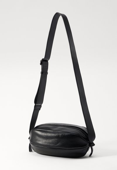 Borsa a tracolla in pelle nera con una texture liscia, forma arrotondata, tracolla regolabile e chiusura con zip. Design semplice, senza motivi o accenti visibili.