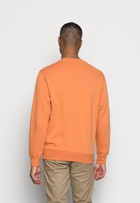 Sudadera naranja con cuello redondo y mangas largas, que presenta un dobladillo y puños acanalados, fabricada en un tejido suave y elástico.