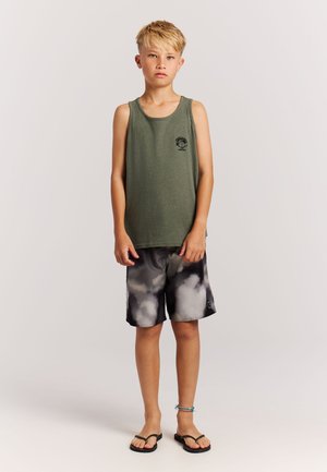 Green tank top with a logo, paired with black and gray tie-dye shorts. The outfit features a relaxed fit and a simple design. Black flip-flops worn.