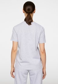 Szary t-shirt z okrągłym dekoltem wykonany z miękkiej bawełny, prezentowany z tyłu. Ma luźny krój i prosty design.