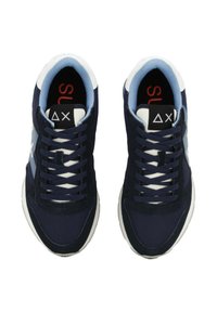 Para granatowo-białych sneakersów z jasnoniebieskim wykończeniem, czarnymi metkami języka z białymi geometrycznymi symbolami oraz granatowymi sznurowadłami.