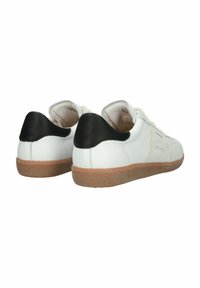 Paire de baskets blanches avec des patchs noirs sur le talon et des semelles en caoutchouc naturel, vues de dos sur fond blanc.