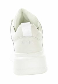 Białe sneakersy widziane z tyłu, z grubą podeszwą, wyściełanym kołnierzem i tkaninowym uchwytem na pięcie.