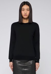 Černý svetr s dlouhým rukávem vyrobený z hladkého materiálu. Má kulatý výstřih a žebrované manžety a lem. Minimalistický design.