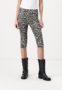 Leopardų rašto capri leggingai pilkos ir juodos spalvos, pasižymintys lygia tekstūra ir lieknu siluetu, derinami su juodais iki kelių ilgiais batais.