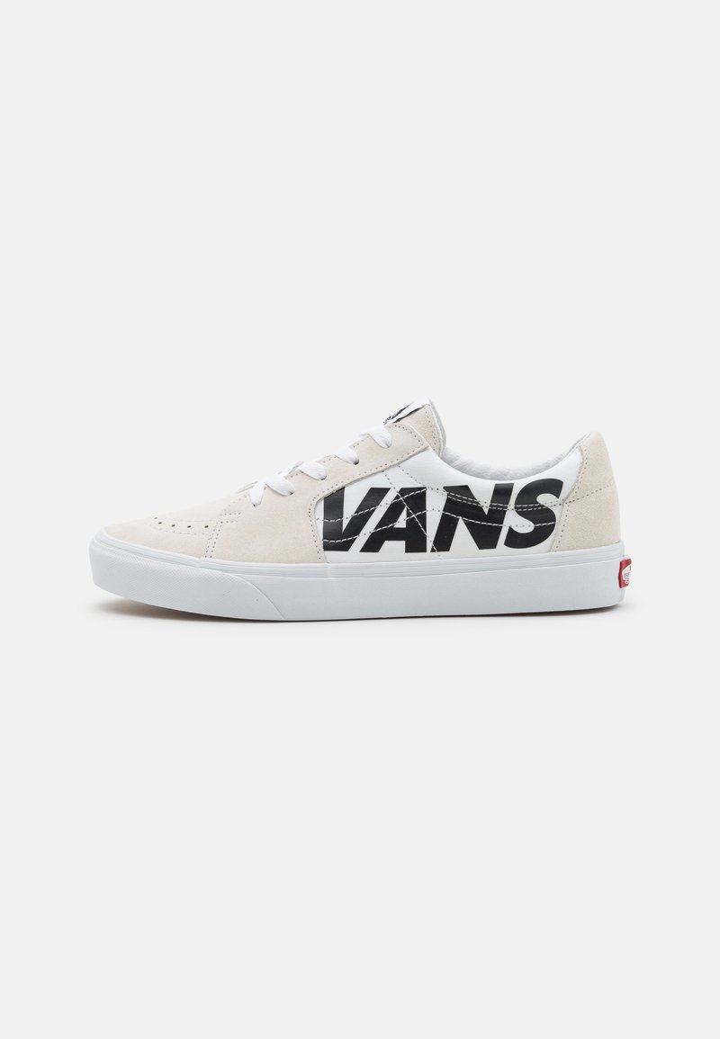 Beiga mocka skateboardskor med en vit mesh-tunga. Stort svart "VANS"-logga på sidan, vita snörningar och vit gummi-sula.