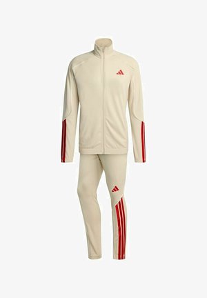 Tuta sportiva beige con strisce rosse sulle maniche e sulle gambe, giacca con zip completa e logo Adidas su petto e coscia.