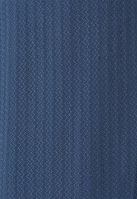 Tejido azul con un patrón de costura en zigzag vertical que crea rayas texturizadas.