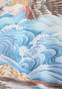 Stoff mit blauen Ozeanwellen, strukturiertem Gittermuster und Schattierungen von Braun, Creme und Teal sowie mit filigranen Details und fließendem Design.