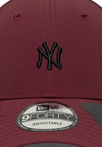 Căciulă ajustabilă maron cu logo-ul NY brodat în negru. Caracteristici: material neted, vizieră rotundă și etichetă circulară New Era în interior.