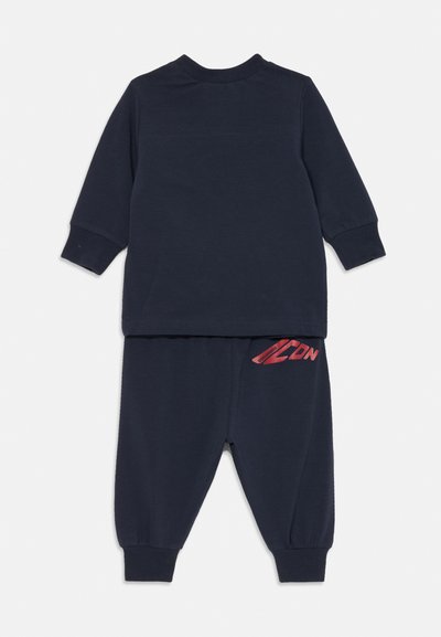 Marineblauwe pullover en bijpassende joggers van zachte katoen. Heeft lange mouwen, elastische manchetten en een rode logo-detail op de broek.