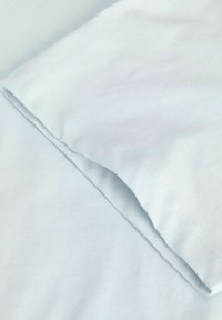Κοντινή εικόνα διπλωμένου ανοιχτού μπλε βαμβακερού υφάσματος που δείχνει ομαλή υφή και ραμμένα ραφές.