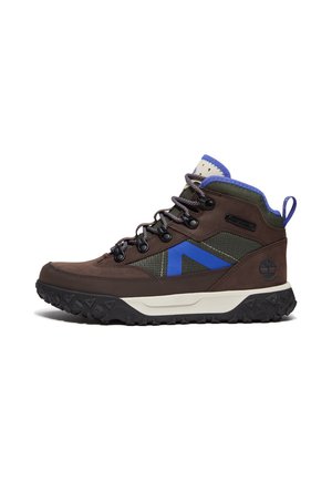 Scarponcino da trekking marrone e verde con accenti blu, suola nera robusta e lacci marroni, mostrato di lato su sfondo bianco.