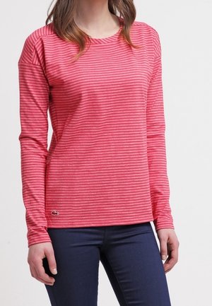 Långärmad t-shirt med rund hals i rosa med vita vertikala ränder. Mjuk tyg med logodetalj vid fållen. Bakgrunden är neutral.
