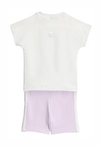 Biała koszula z krótkim rękawem z logo Adidas oraz fioletowe spodenki z białymi paskami po bokach. Mieszanka bawełny, gładka tekstura, casualowy strój sportowy.