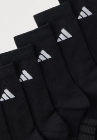 Calcetines negros hasta el tobillo hechos de mezcla de algodón, con el logo blanco de Adidas en la parte superior. Textura acanalada, paquete de seis pares.
