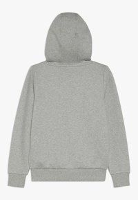Sudadera gris con un acabado texturizado, que cuenta con una capucha amplia, mangas largas y un dobladillo y puños de canalé. Sin logotipos ni patrones visibles.