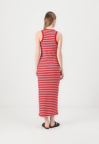 Robe maxi rayée rouge et blanche avec une texture côtelée, sans manches et silhouette ajustée, arrivant aux chevilles.