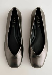 Bailarinas metálico grises con diseño de punta afilada, textura suave y interior acolchado. Nombre de la marca visible dentro del zapato.