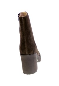 Stivaletto in suede marrone con tacco a blocco alto, chiusura con zip laterale e suola liscia, che mette in mostra una silhouette affusolata e una texture ricca.