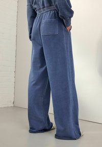 Pantalons de survêtement bleu ample en coton doux. Dotés d'une taille élastique, de poches latérales et d'une poche arrière avec un ourlet effiloché.