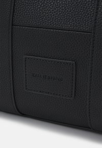 Sac en cuir synthétique noir texturé de forme rectangulaire, avec une étiquette de marque "CALL IT SPRING" cousue sur la surface.