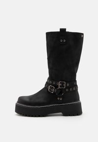 Botines negros de ante, con suela de plataforma gruesa, hebillas decorativas y acentos metálicos. Caño vertical con un asa en la parte superior.