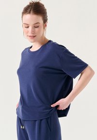 T-shirt a maniche corte blu navy in tessuto leggero, con scollo rotondo e vestibilità comoda, dotato di spacco ai lati per facilitare i movimenti.