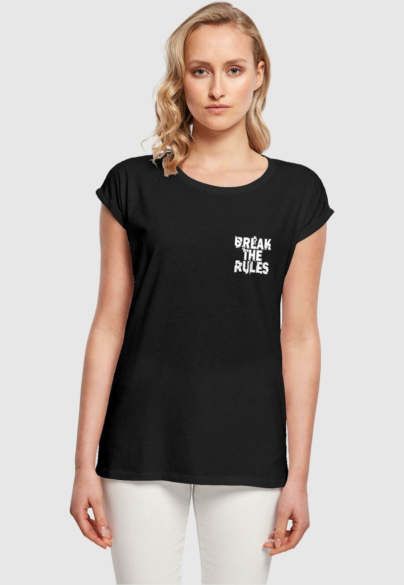 Sort bomuld t-shirt med korte rullede ærmer, der har hvid tekst "BREAK THE RULES" på venstre front. Enkel, afslappet design.