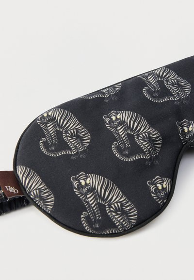 Μάσκα ύπνου με μαύρο ύφασμα που έχει ρίγες με τίγρεις σε γκρι και άσπρο. Μαλακή υφή και ελαστική ταινία για ασφαλή εφαρμογή.