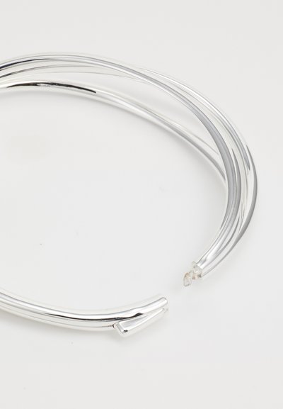Bracelet en métal argenté avec un design lisse et arrondi ; présente deux bandes entrelacées et une coupure à une extrémité.