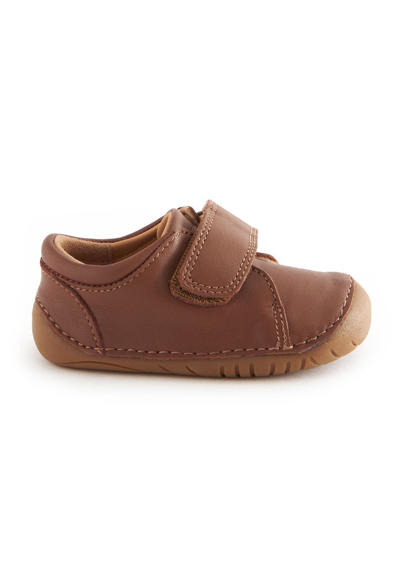 Chaussure en cuir marron avec une sangle à velcro, bout rond et semelle en caoutchouc. Présente des accents cousus, un intérieur doux et un profil bas.