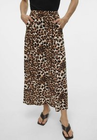 Gonna maxi in stampa leopardata realizzata in tessuto morbido, con vita elastica nera e tasche laterali. Presenta motivi marroni, neri e bianchi.
