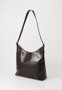 Brown leather shoulder bag with a smooth finish, curved top, and adjustable strap. Features a zip closure and minimalistic design.