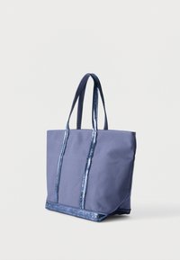 Sac fourre-tout en tissu bleu avec deux longues anses et une bordure de sequins brillants le long des anses et du bord inférieur, présenté sur un fond uni.