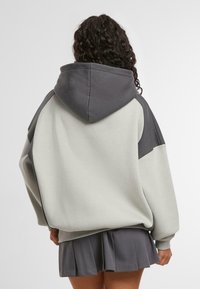 Hettegenser med to-tonet design i lys grå og mørk grå, myk stoff, løs passform, med ribbede mansjetter og falmer.