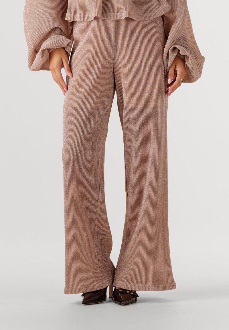 Lichtroze, ribbelige wijde broek met een zachte textuur en subtiele glans. Gecombineerd met pointed-toe, donkerbruine hakken.